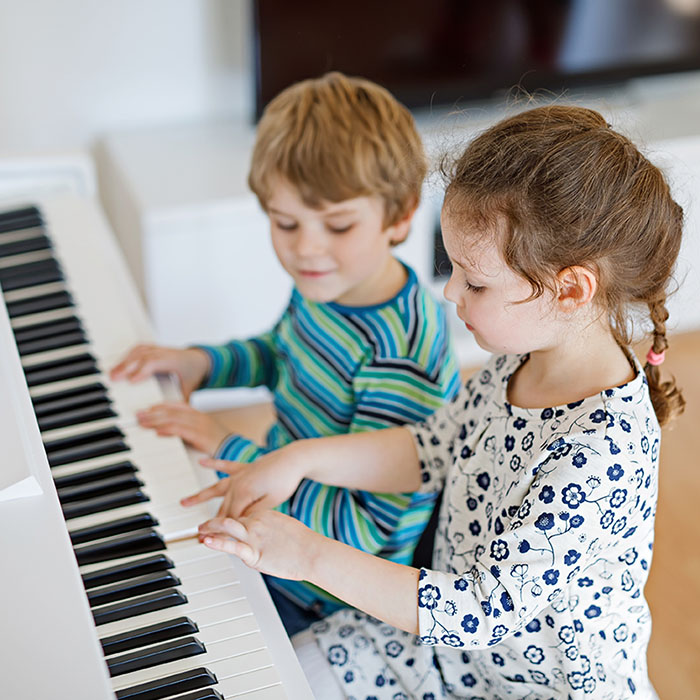 Zimmerlautstärke bei Musik: Zwei Kinder spielen Klavier